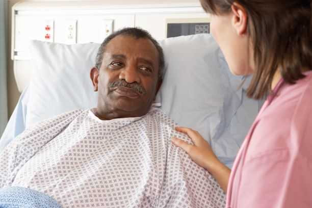 Nurse comforts older man in hospital bed